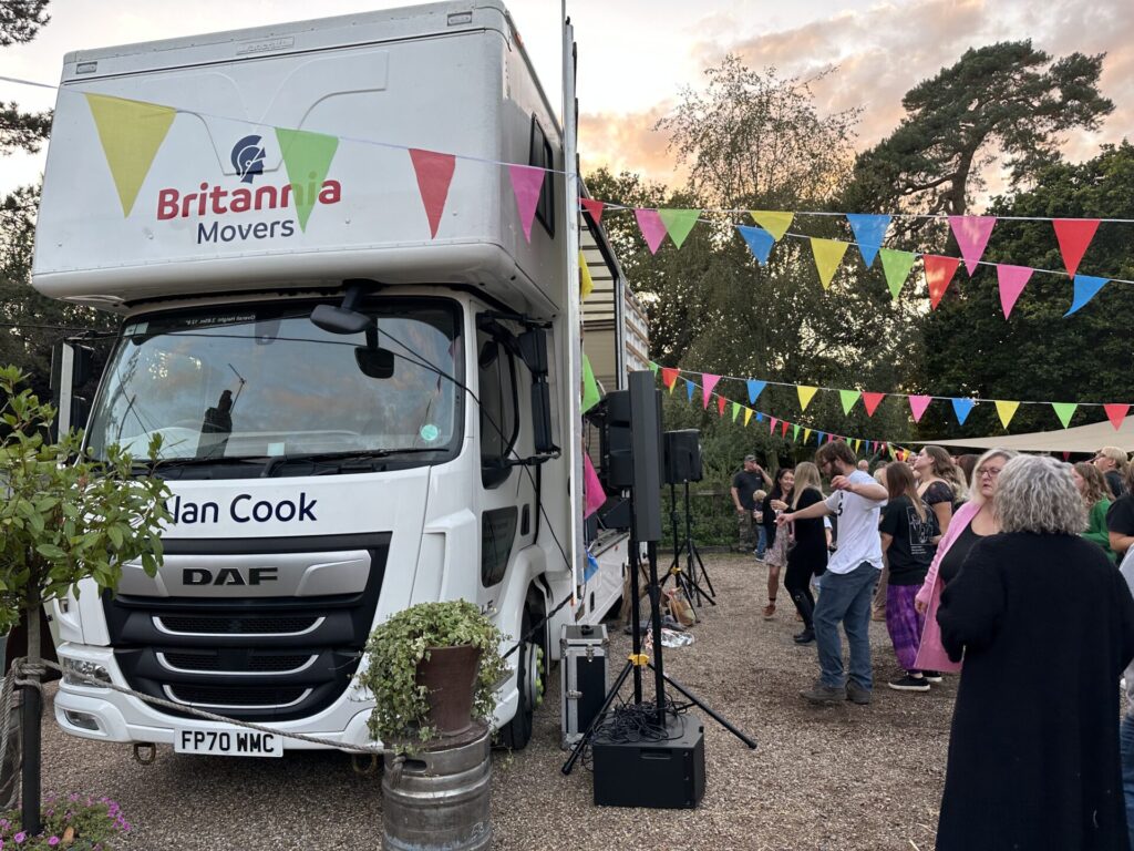 Van with Britannia Movers and Alan Cook logos in a pub garden with bunting and people dancing