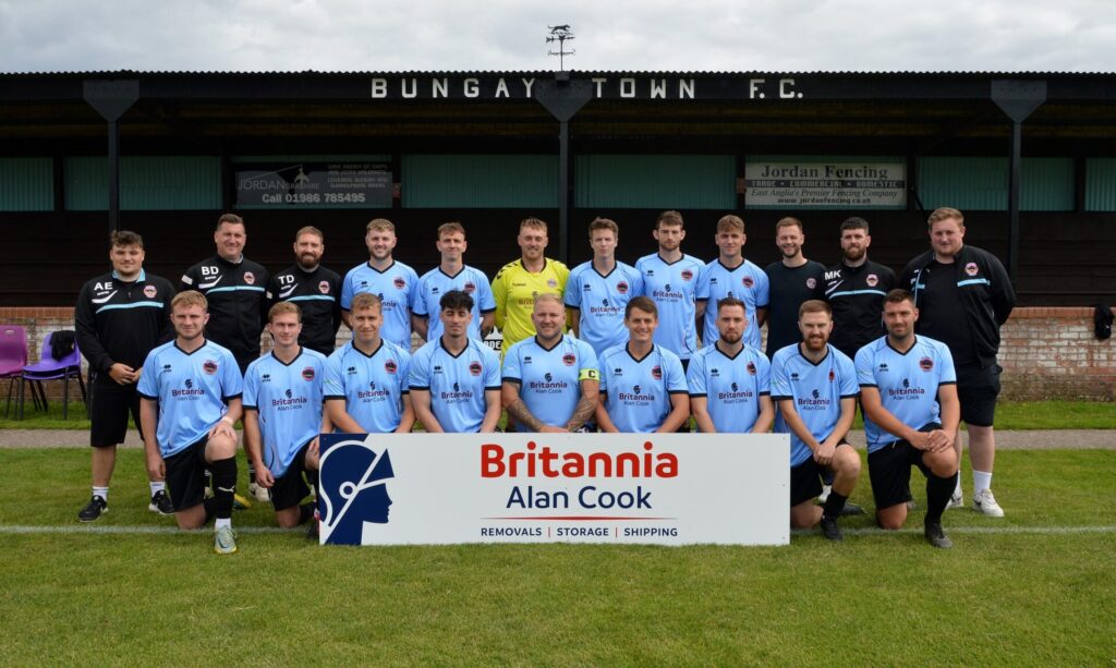 Football team posing with a sign that reads "Britannia Alan Cook Removals, Storage, Shipping"